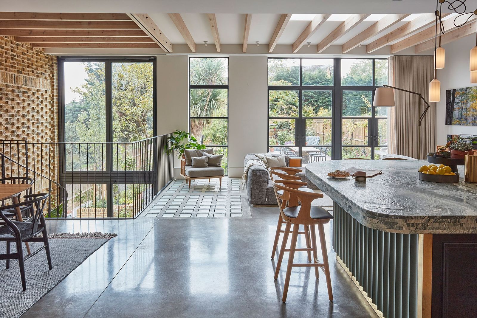 Expansive kitchen and dining volume with polished concrete floor and fluted island