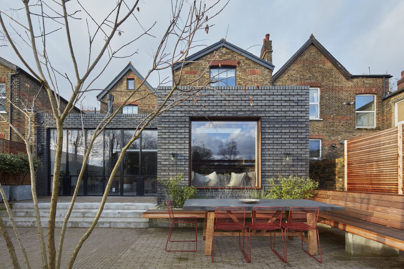 Rear extension in dark engineering brick with a full-height picture window and terrace