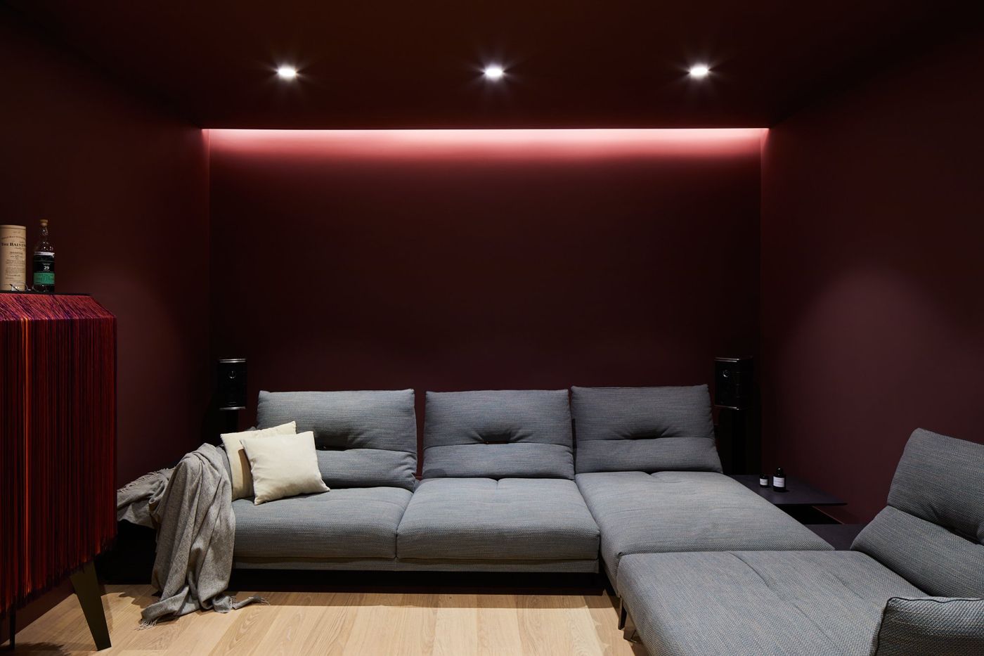 Basement cinema room with deep red walls and a wide grey sofa