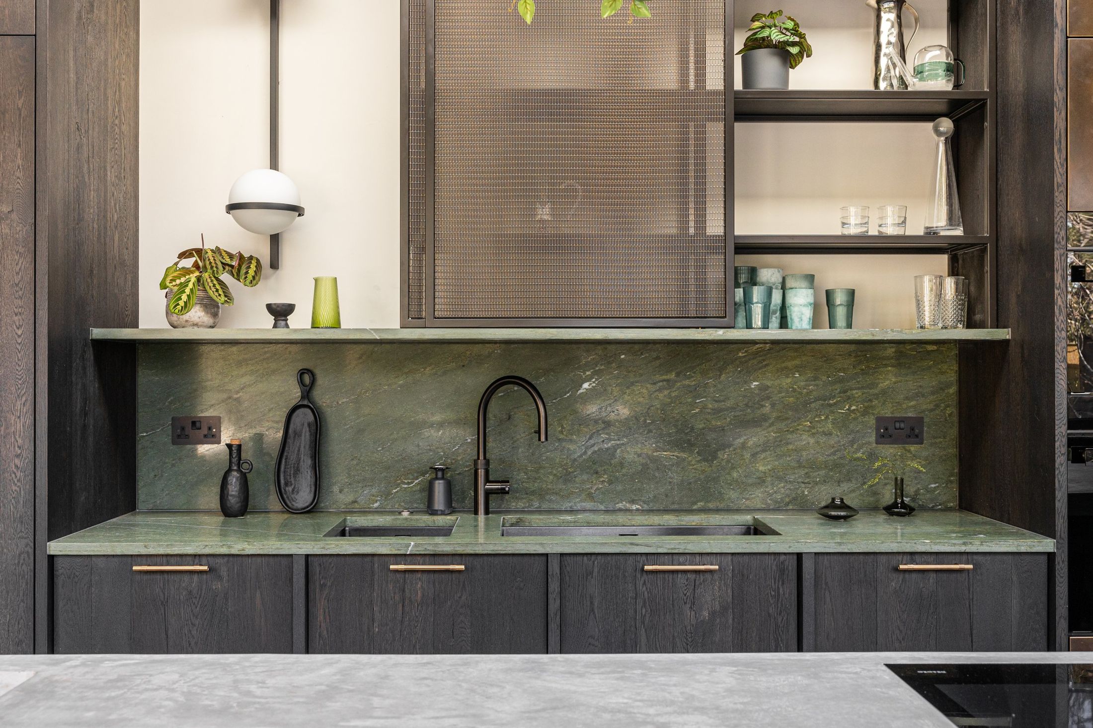 Kitchen in dark-stained oak with a green marble splashback and worktop