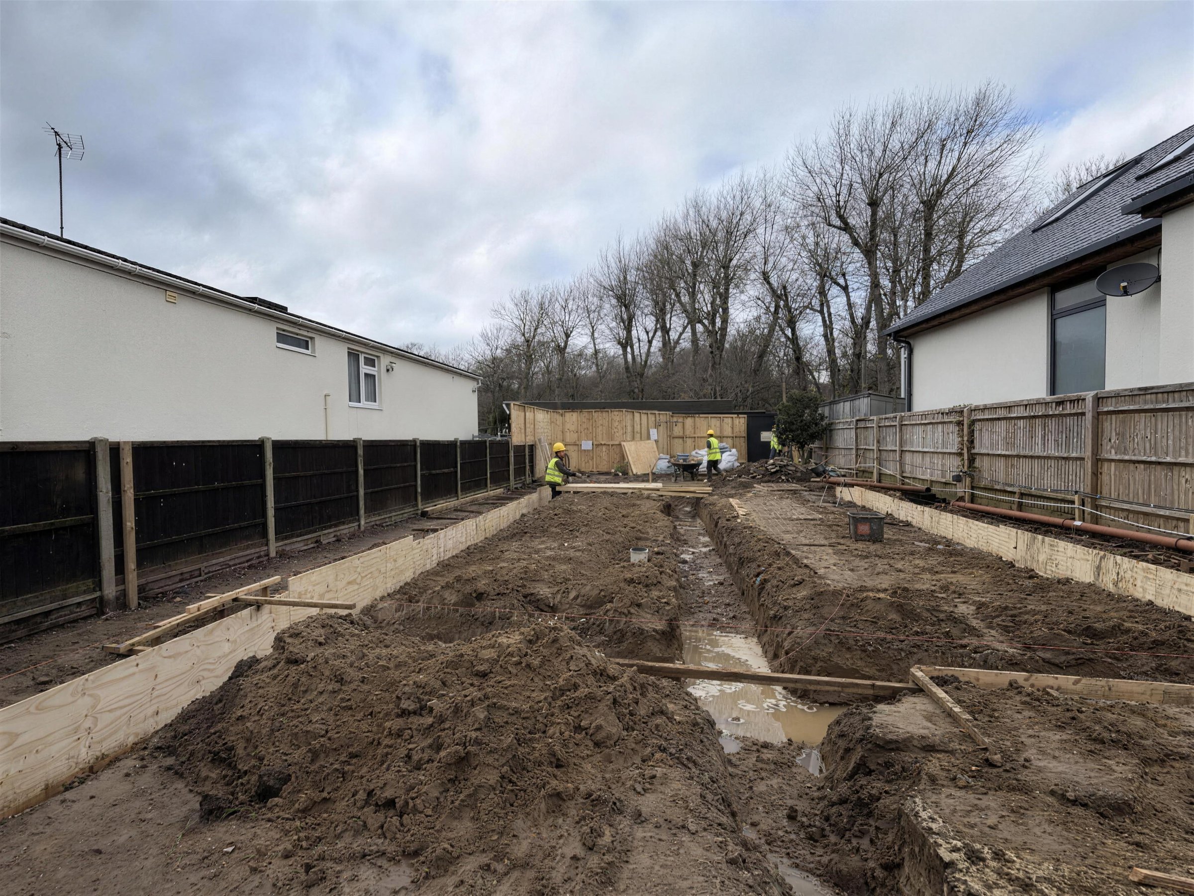Excavated plot with plywood shuttering set up for the ground beams and the central trench dug to line