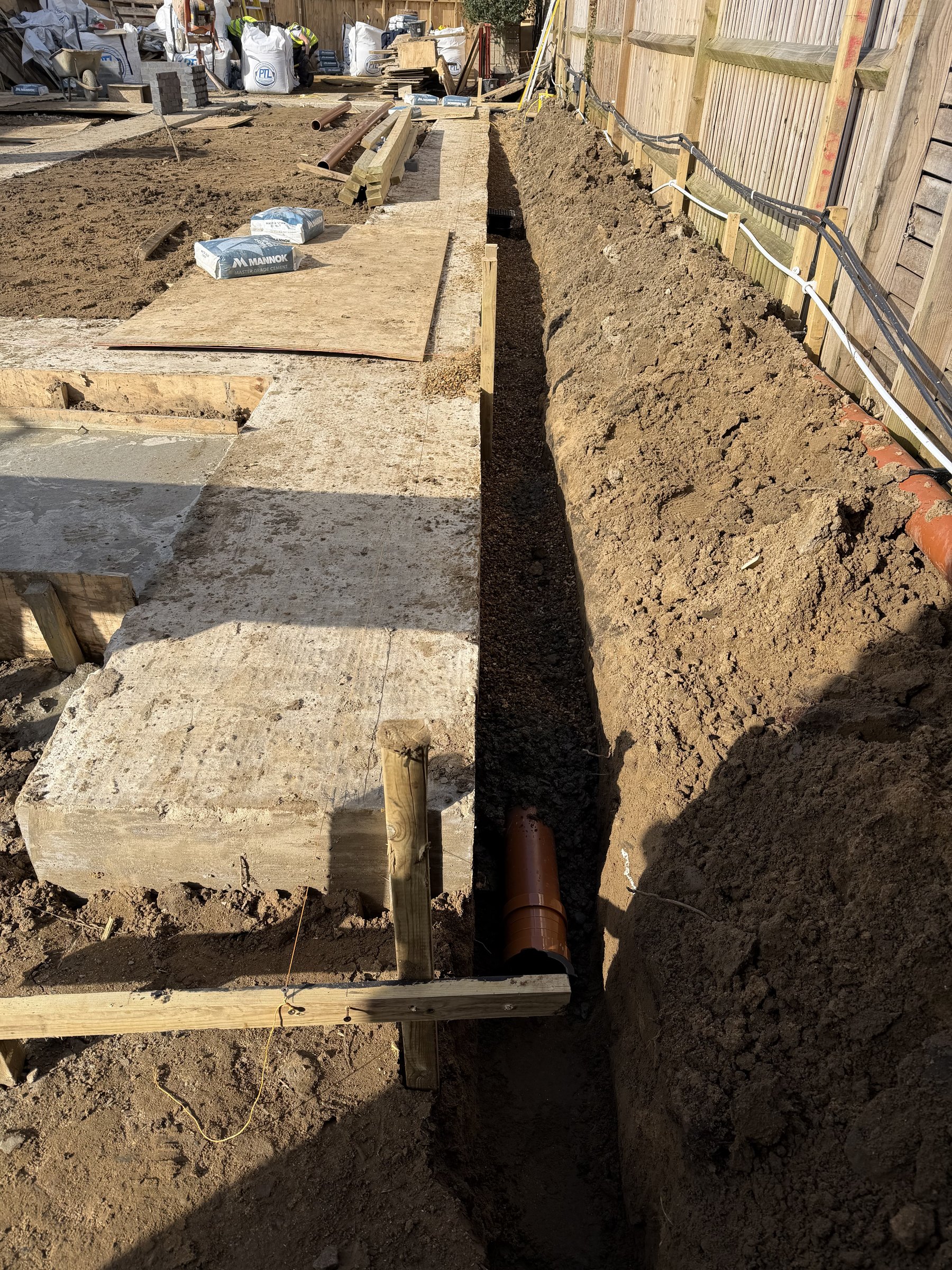 Cast concrete ground beam with a drainage run bedded in gravel alongside it