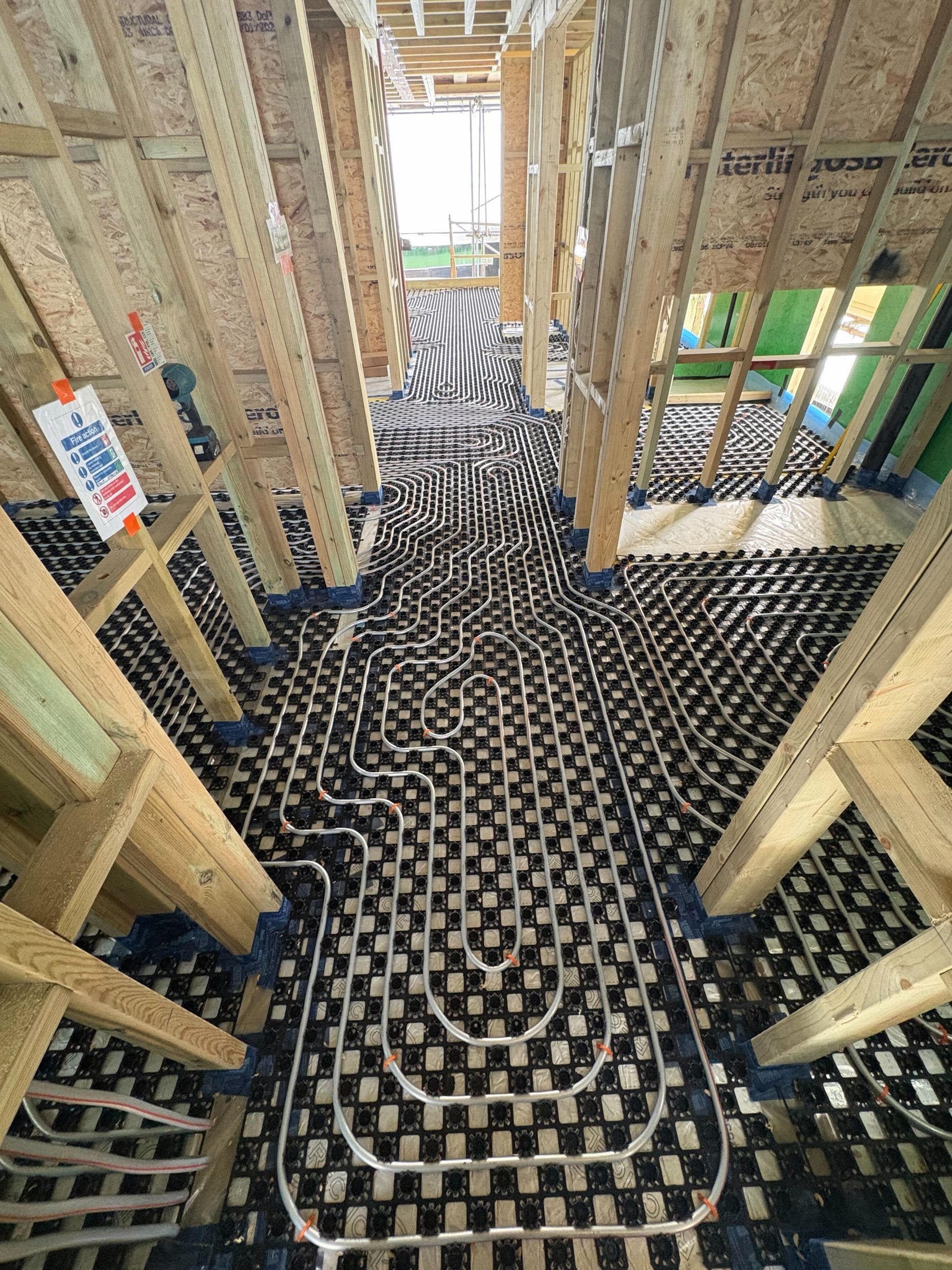 Heating pipe runs threading room to room through the timber frame