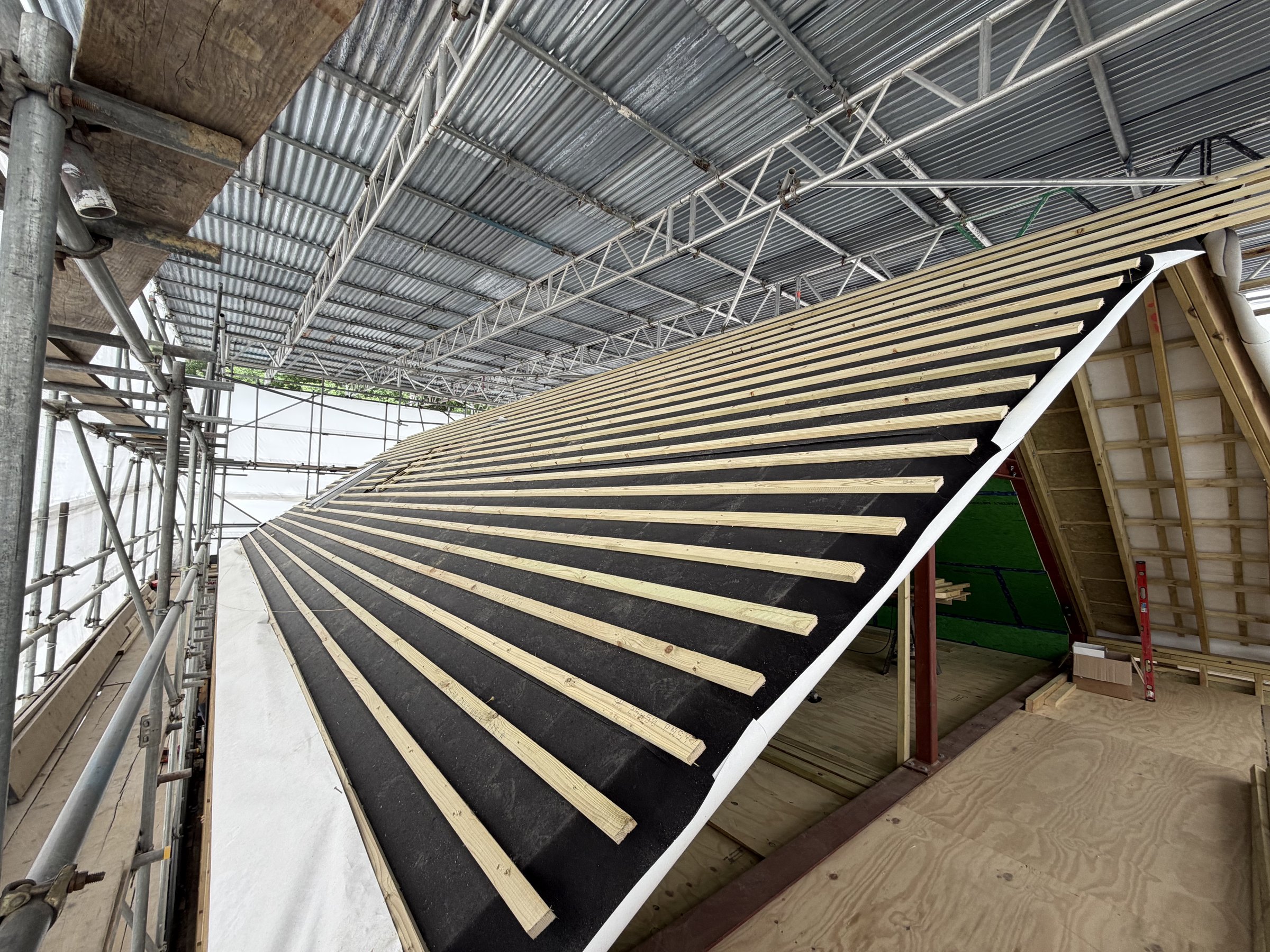 Counter battens and tile battens over dark breather membrane under the scaffold canopy
