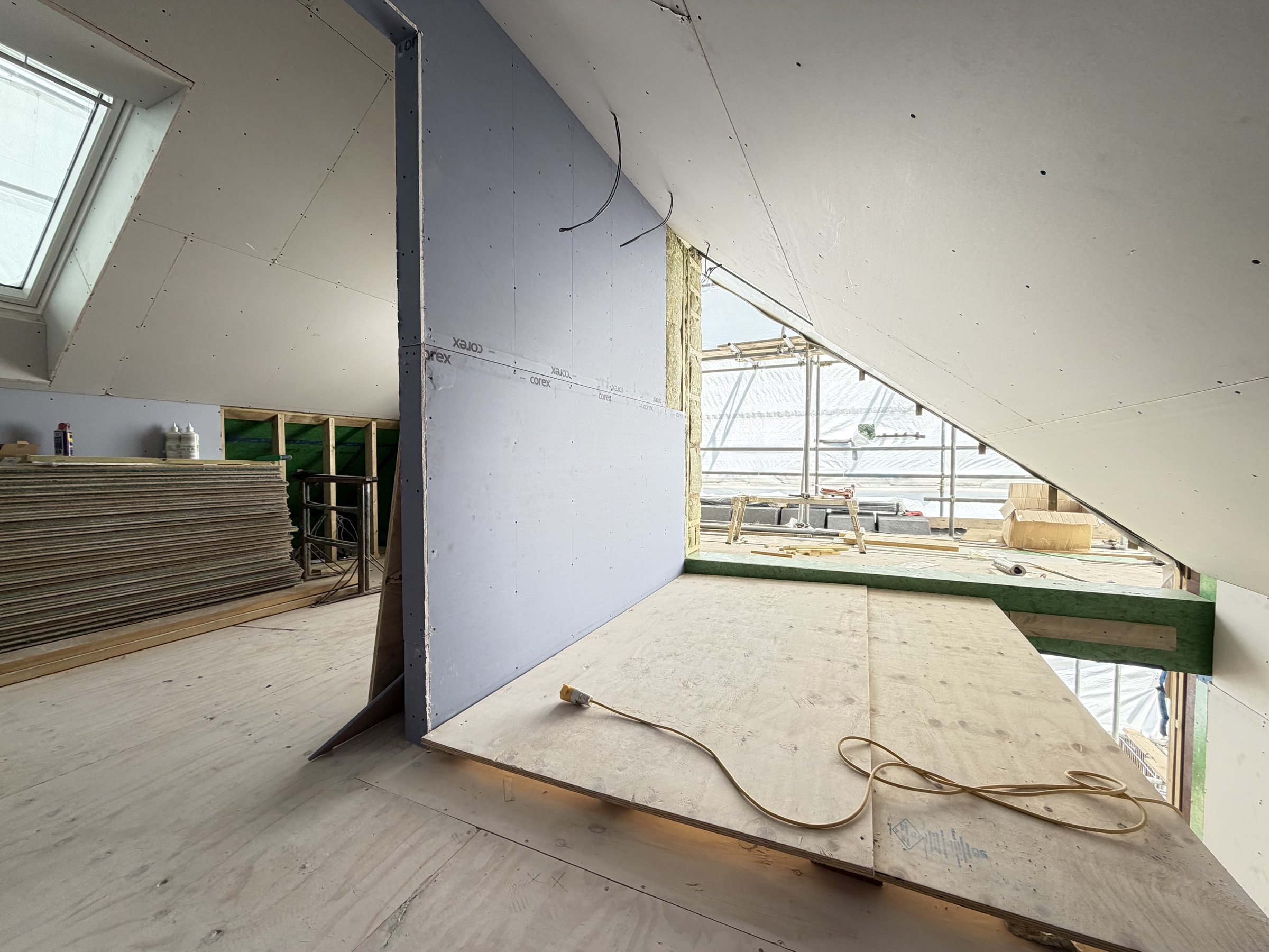 Loft room boarded out to the roofline with rooflights glazed and more plasterboard stacked ready