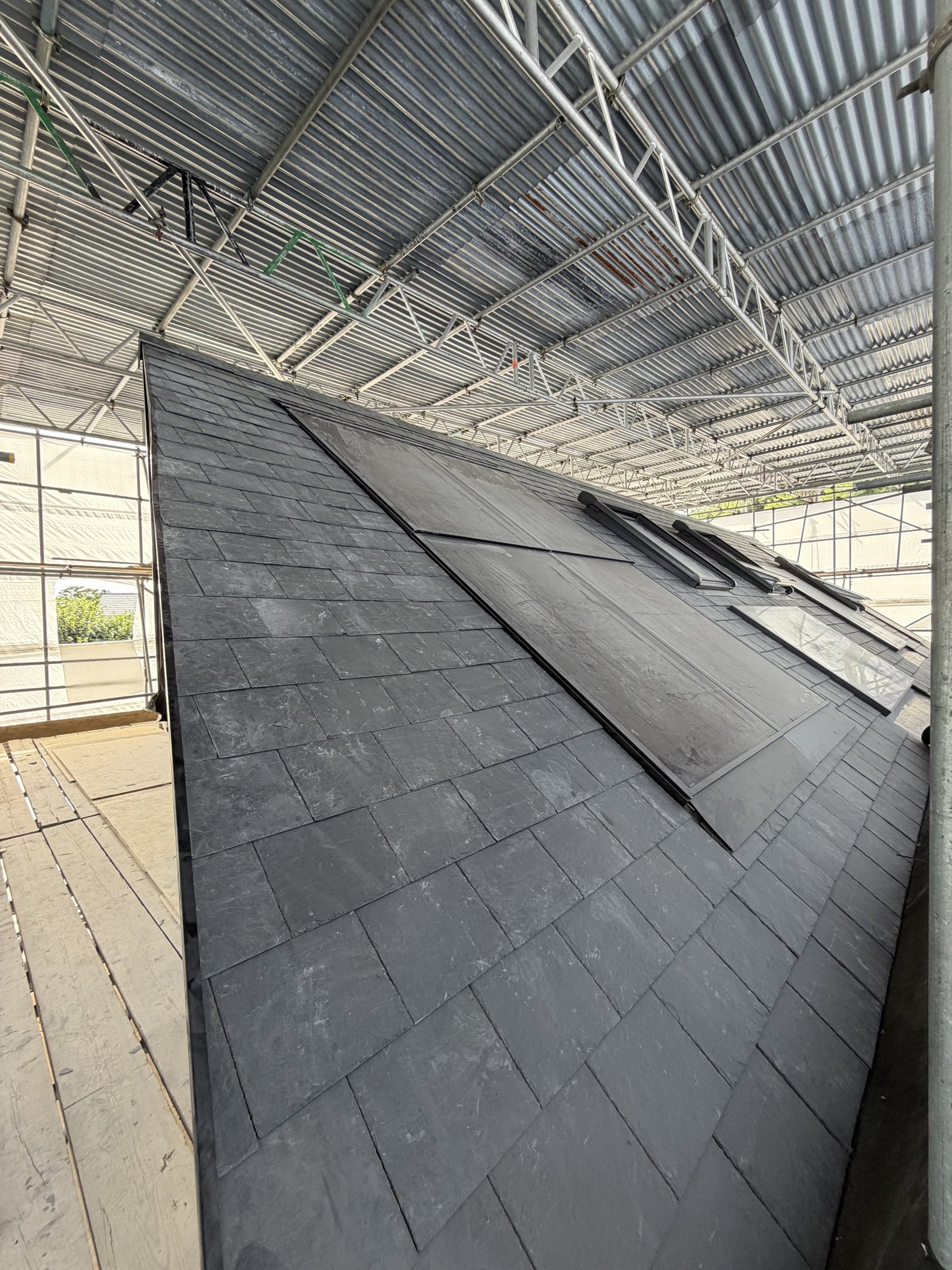 Two in-roof solar panels set flush in the rectangular slates, a rooflight beyond