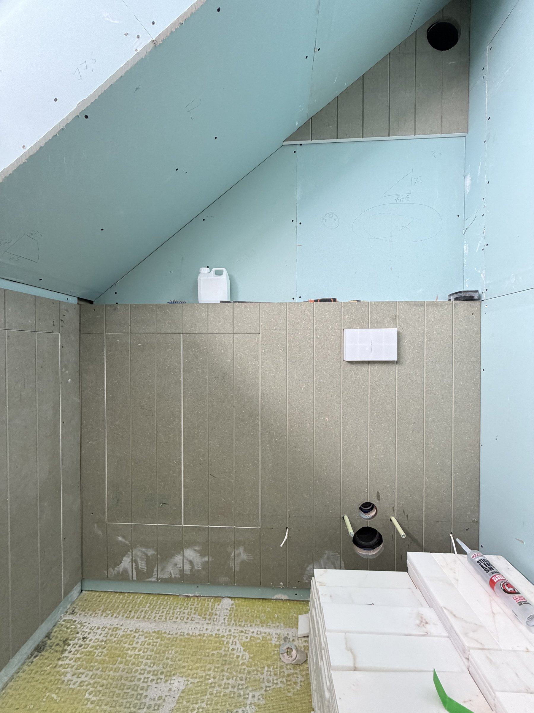 Loft bathroom with tile backer board to the lower walls, decoupling mat on the floor and tiles stacked ready
