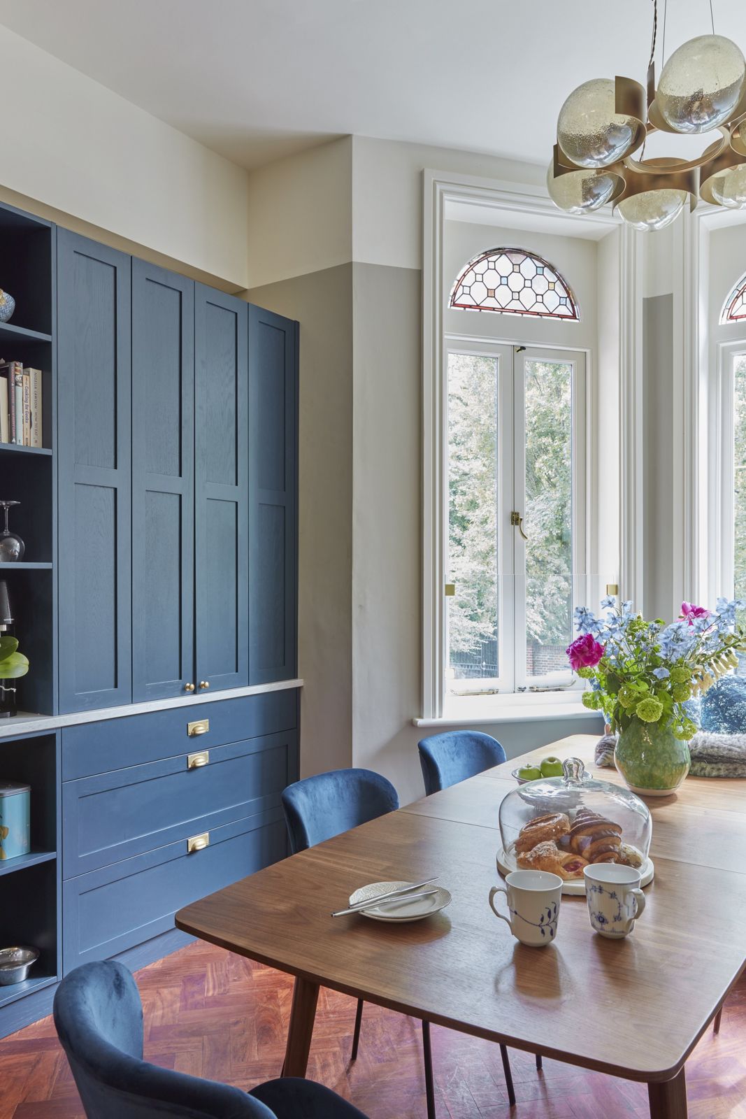 Blue cabinetry beside the dining table with garden light