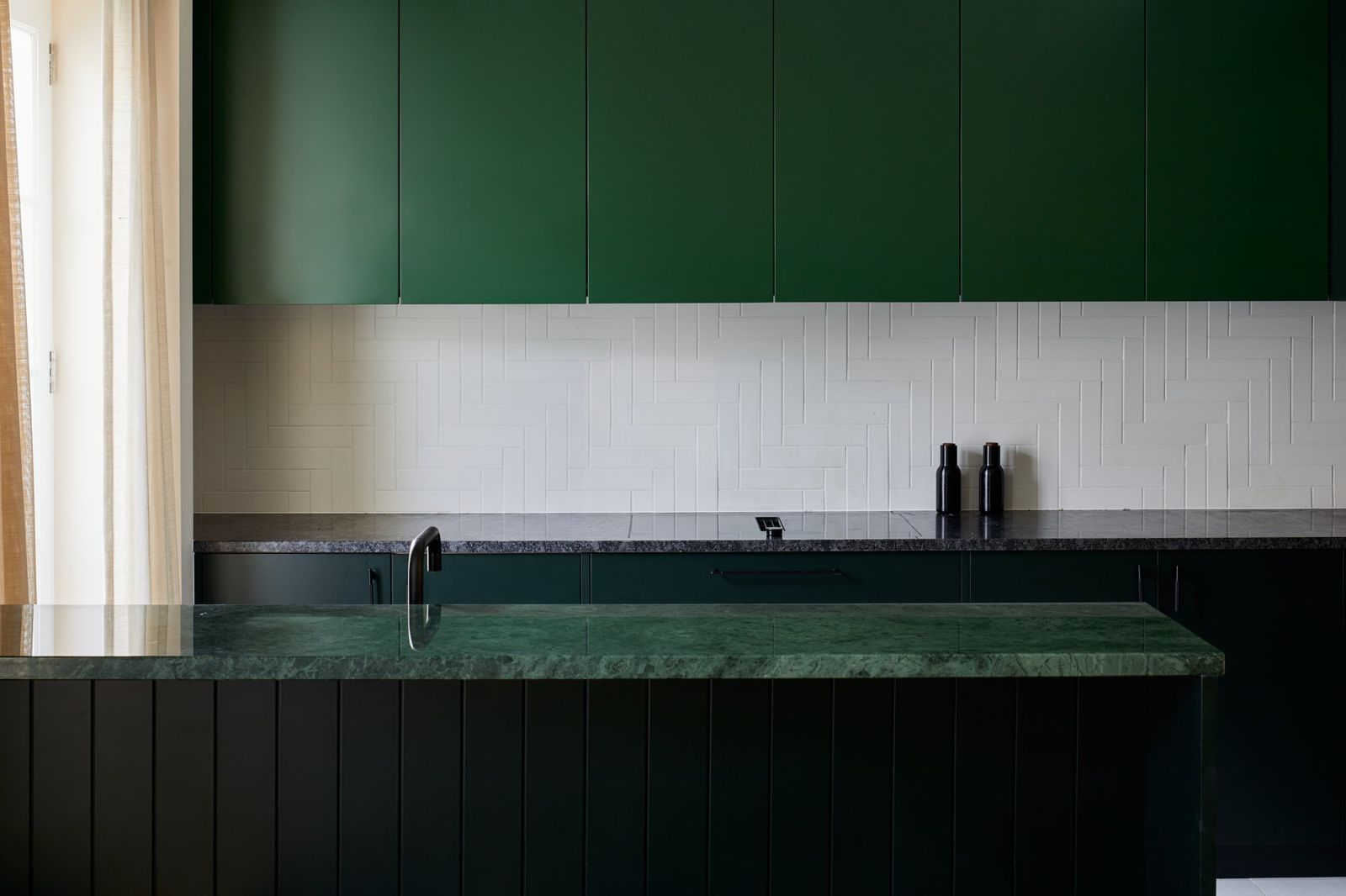Dark green kitchen with green stone worktop and splashback