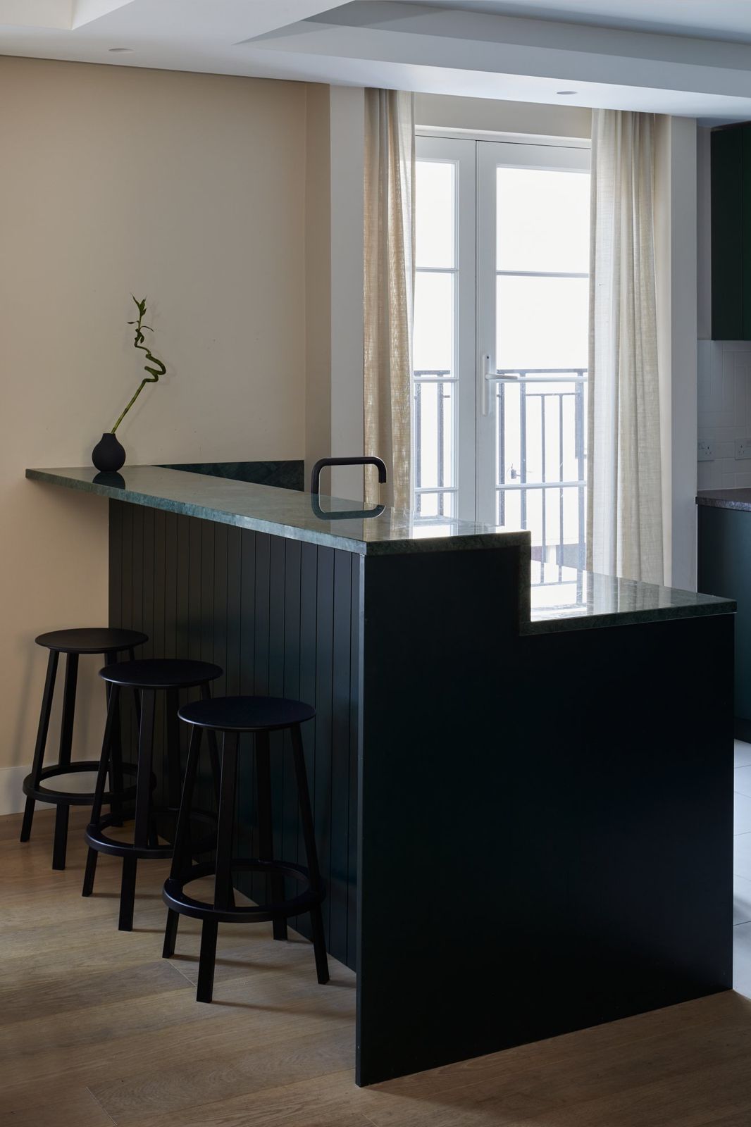 Home bar in dark joinery with stools