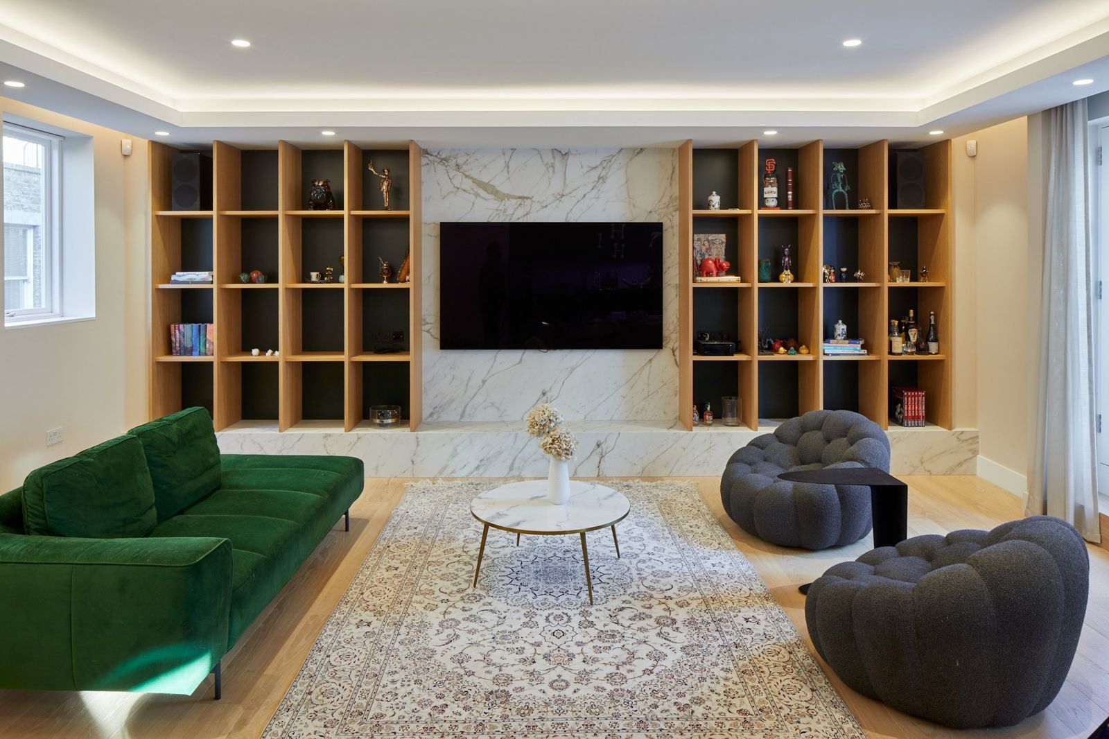 Living room with green velvet sofas and marble media wall