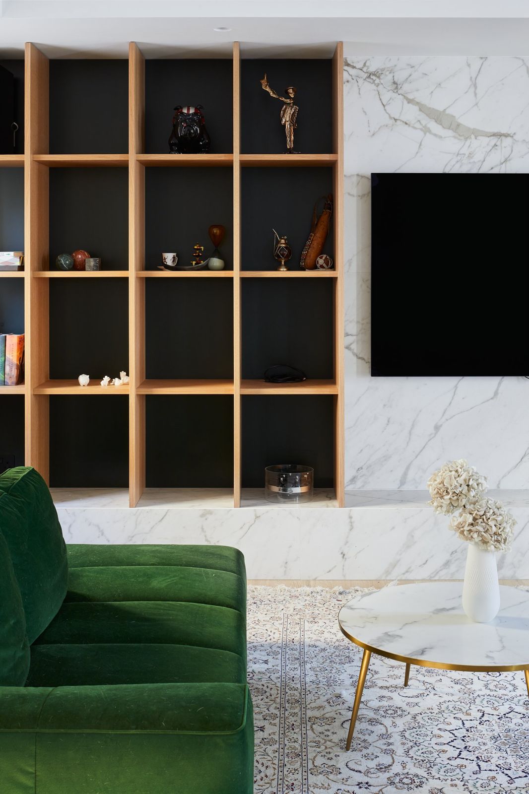 Oak shelving beside a marble-clad media wall
