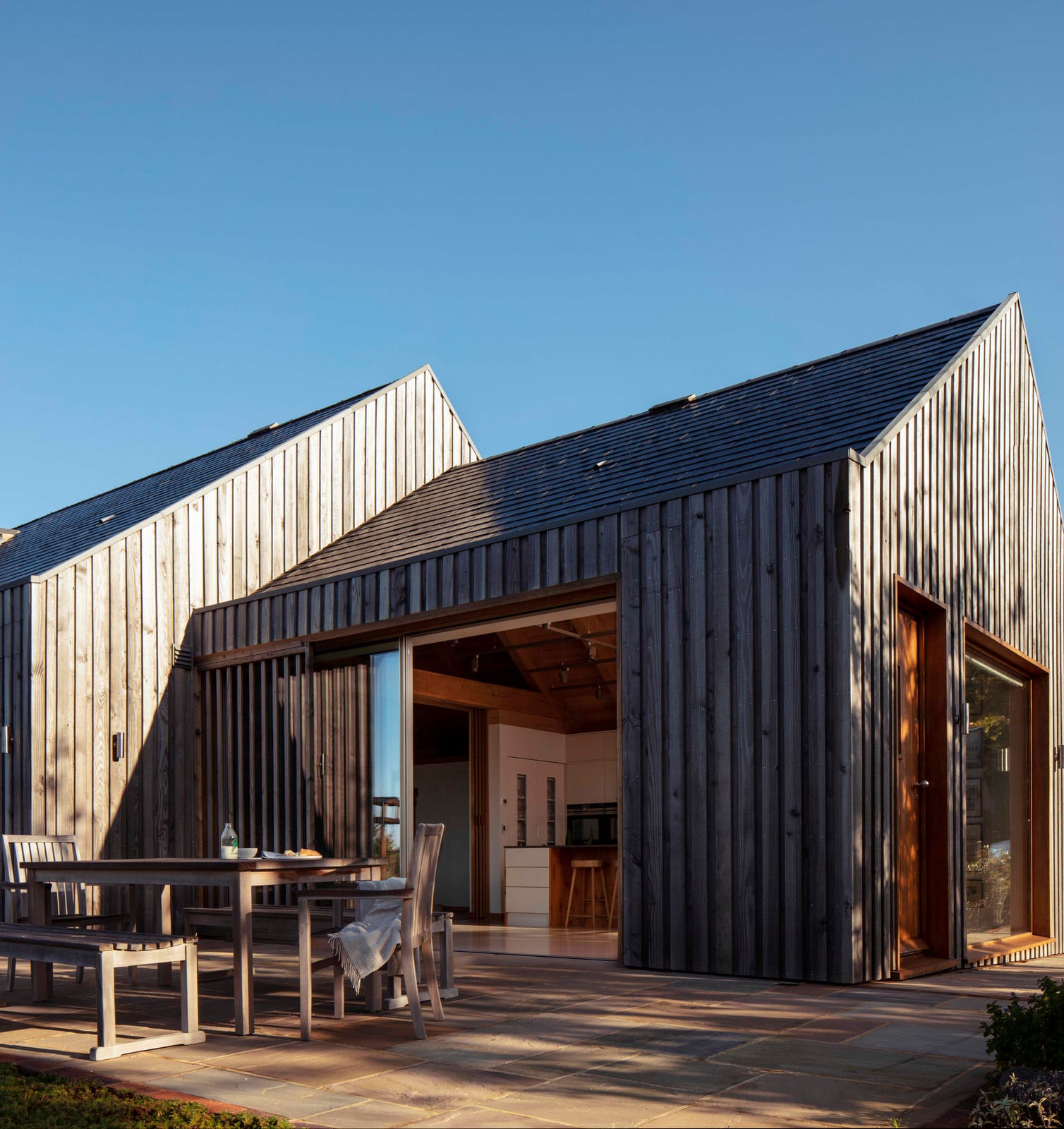 Weathered timber gable and terrace with sliding doors open to the kitchen