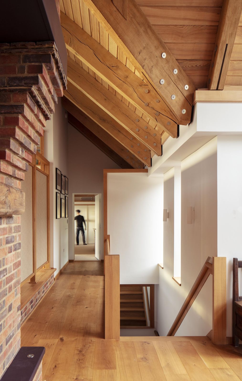 Exposed timber roof structure over the stair landing beside a brick wall