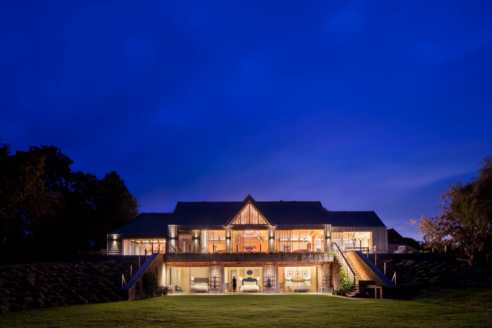 The lit house seen across the lawn at nightfall