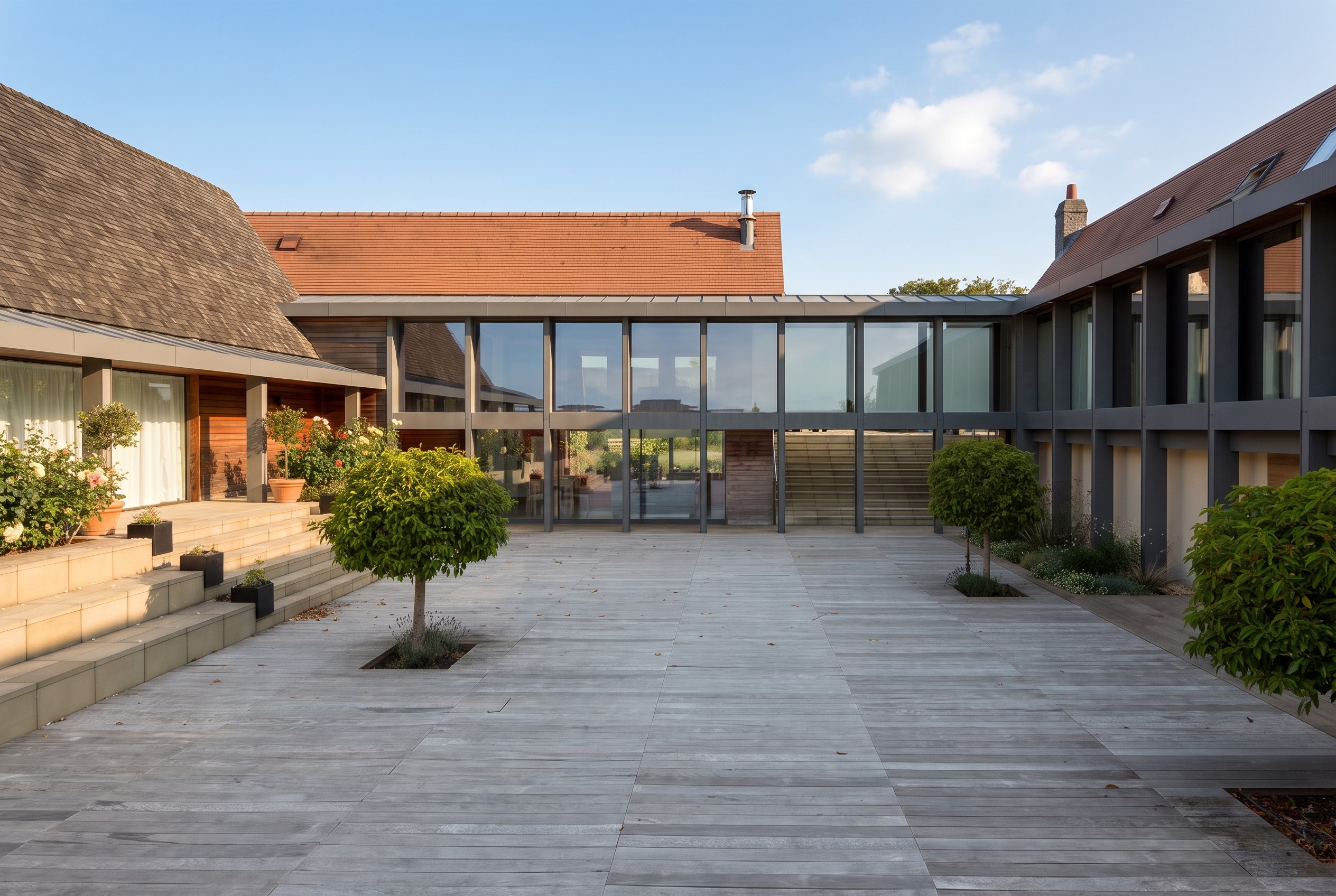 Double-height glazed link between two tiled wings, seen across the courtyard