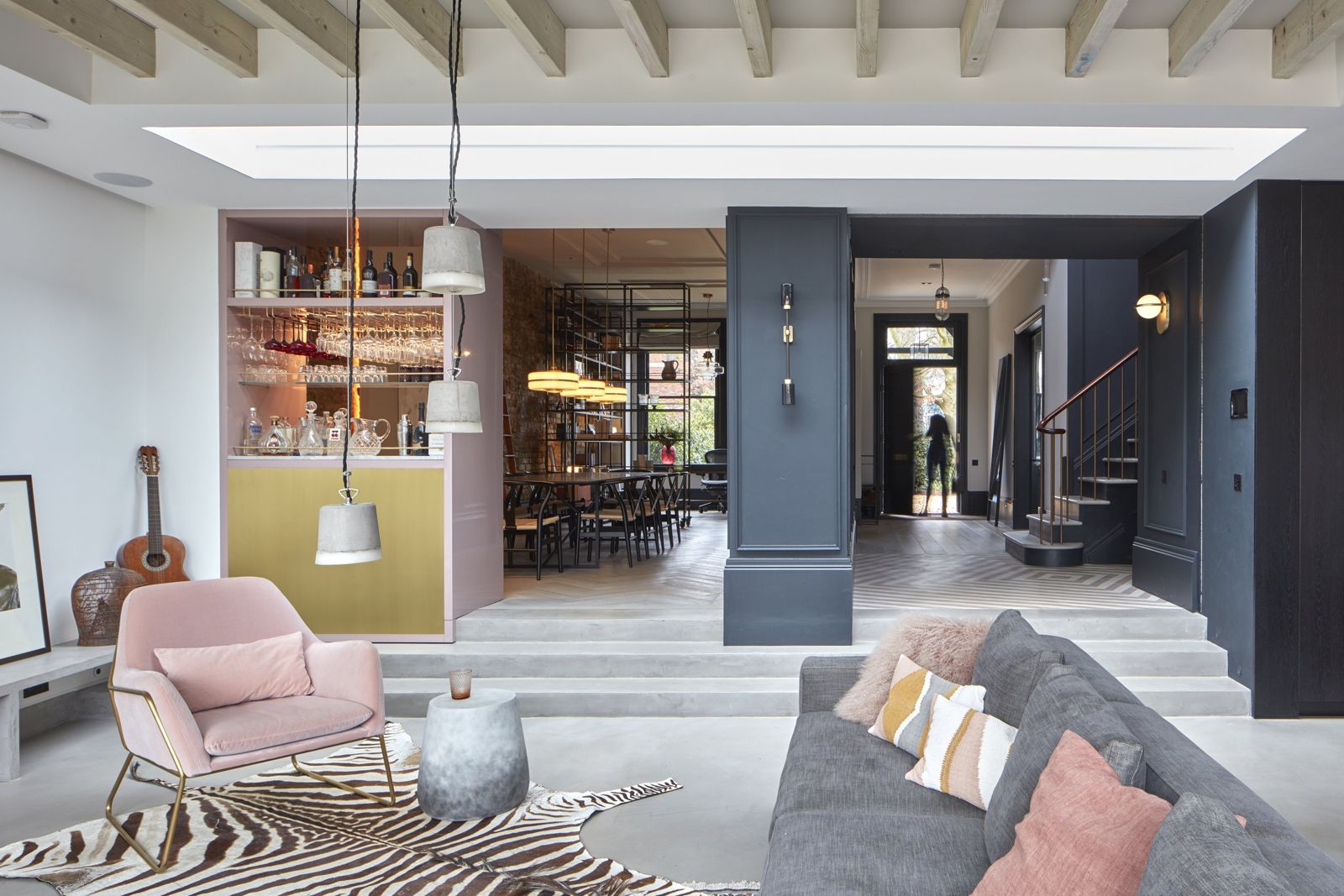 Sunken lounge with pink armchairs beside a dark feature wall
