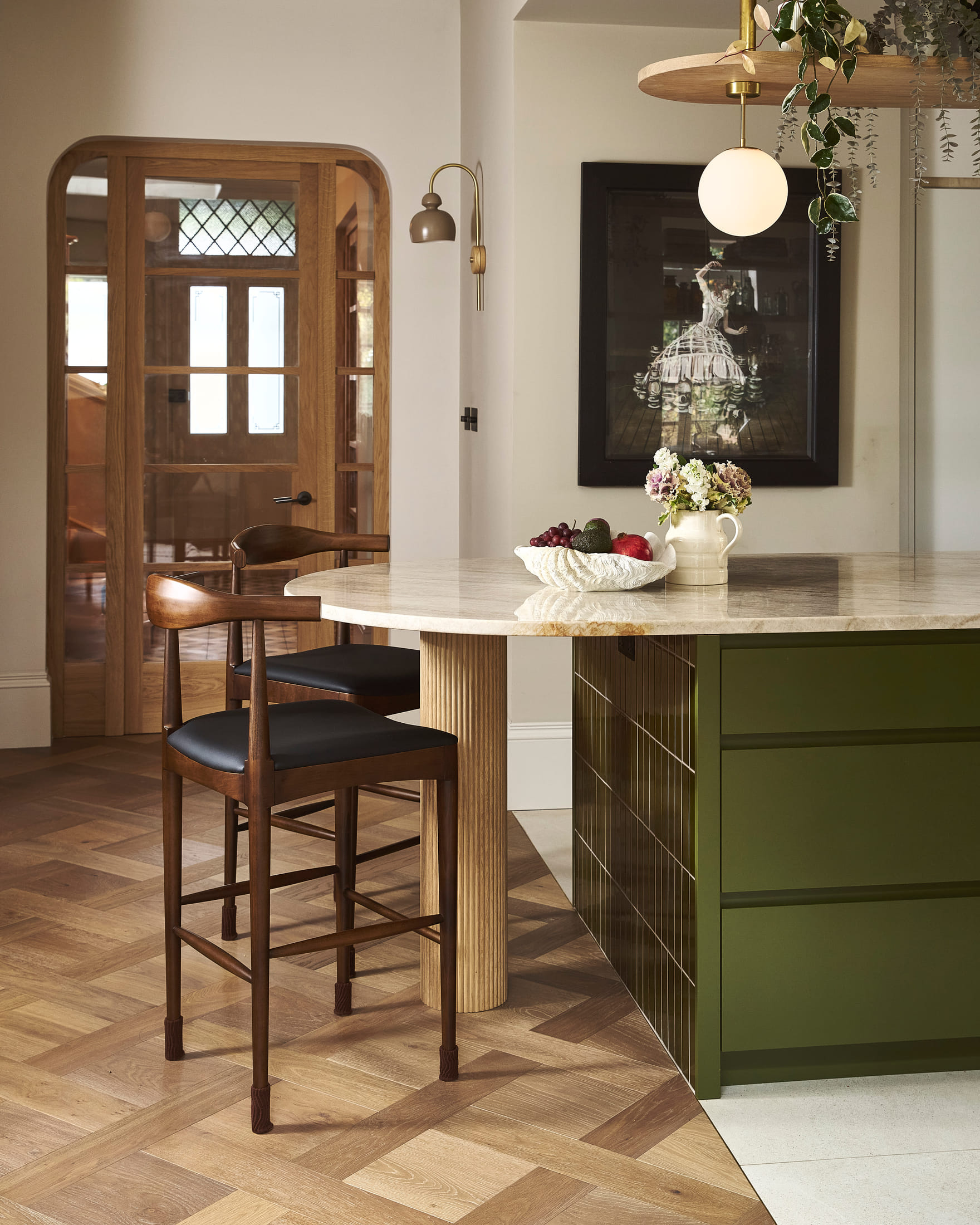 Fluted stone drum carrying a travertine table, with the arched oak door to the hall beyond