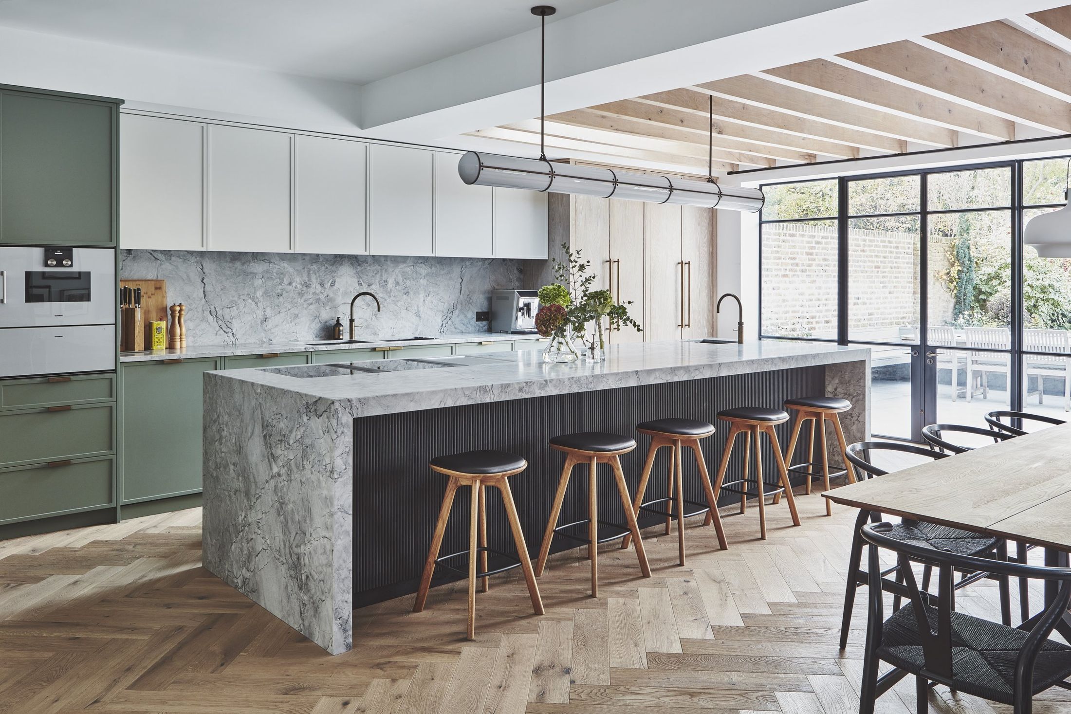 Open-plan kitchen with green panelled joinery and a four-metre marble island