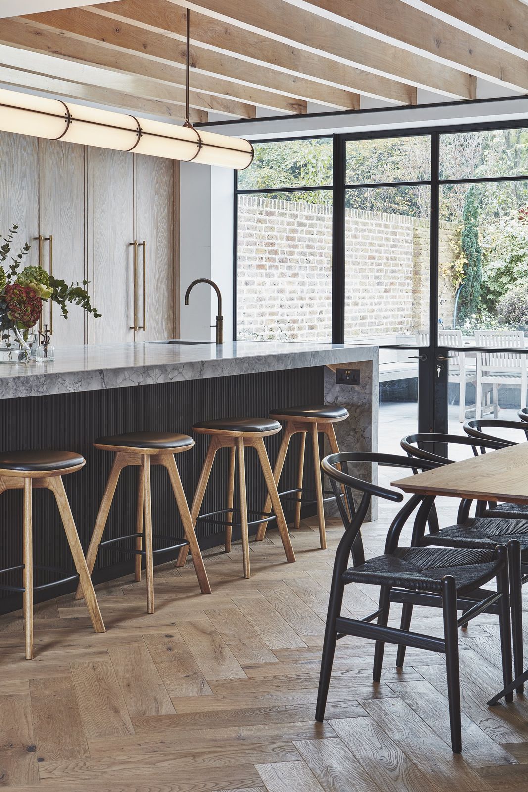 Marble island with oak stools under exposed ceiling joists