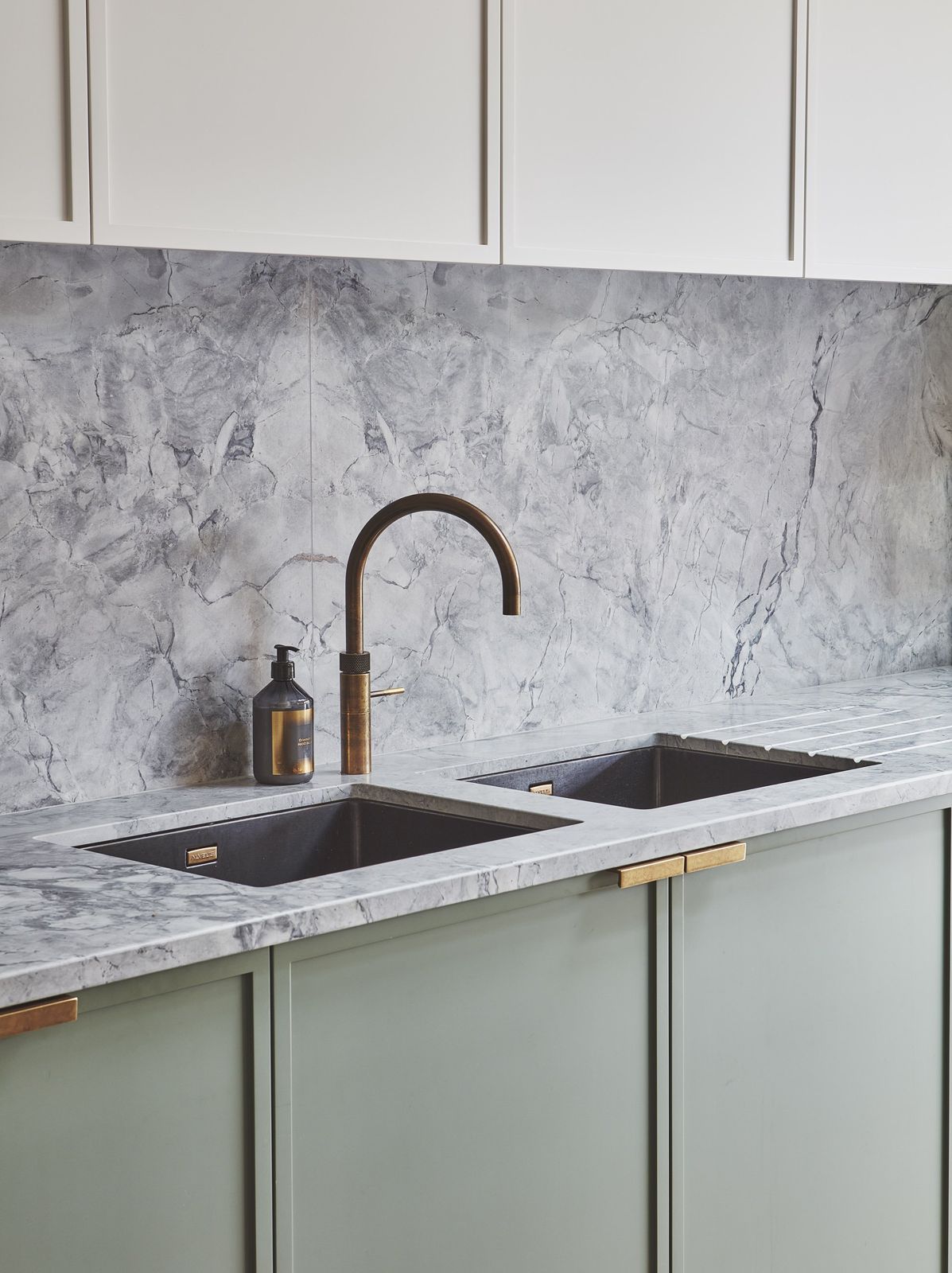 Grey marble splashback with brass tap over a green kitchen run