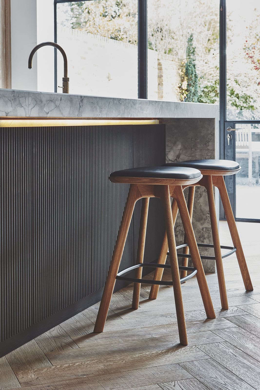 Dark fluted island with timber stools