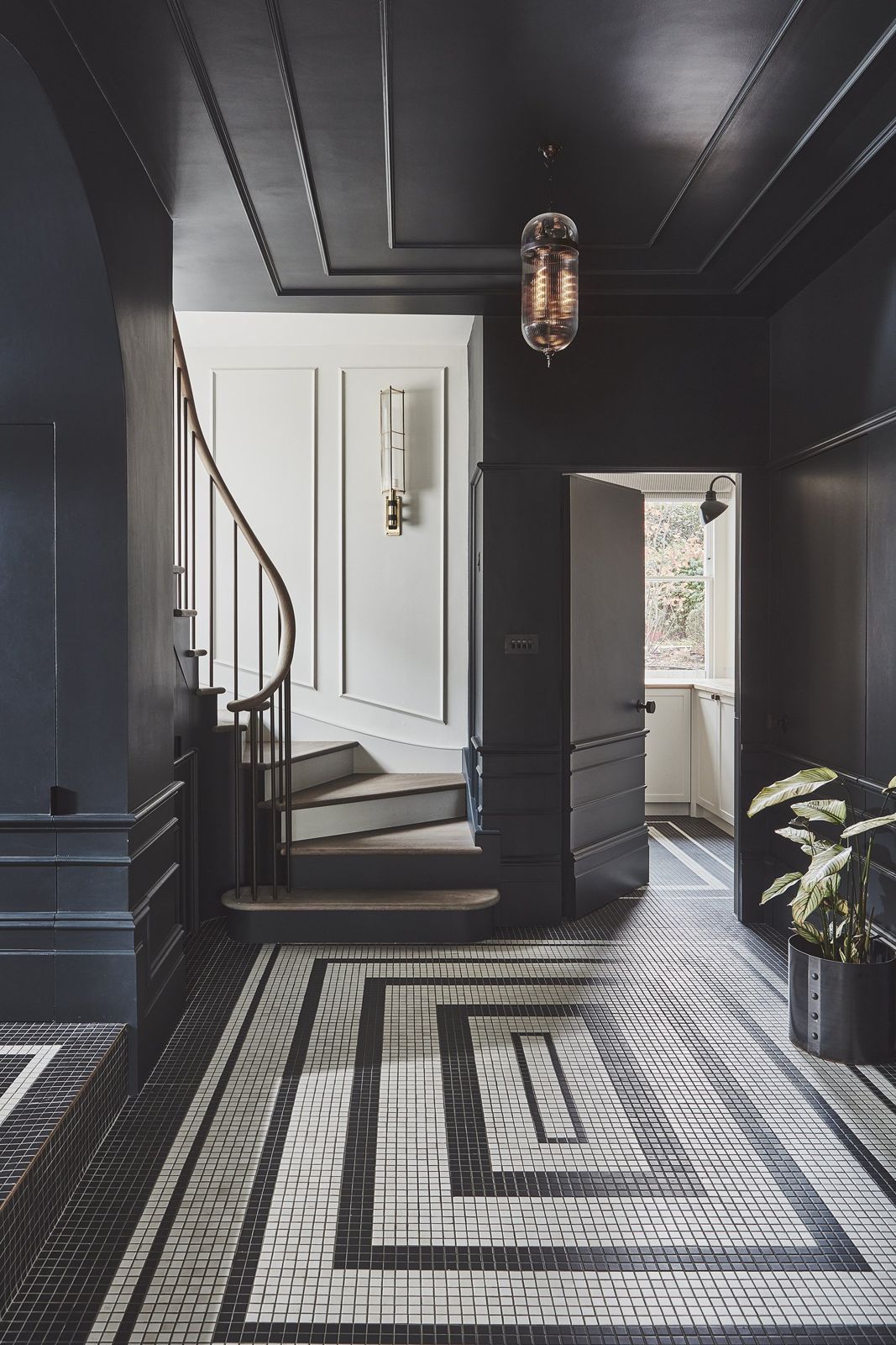 Dark entrance hall with mosaic floor and a curved period staircase