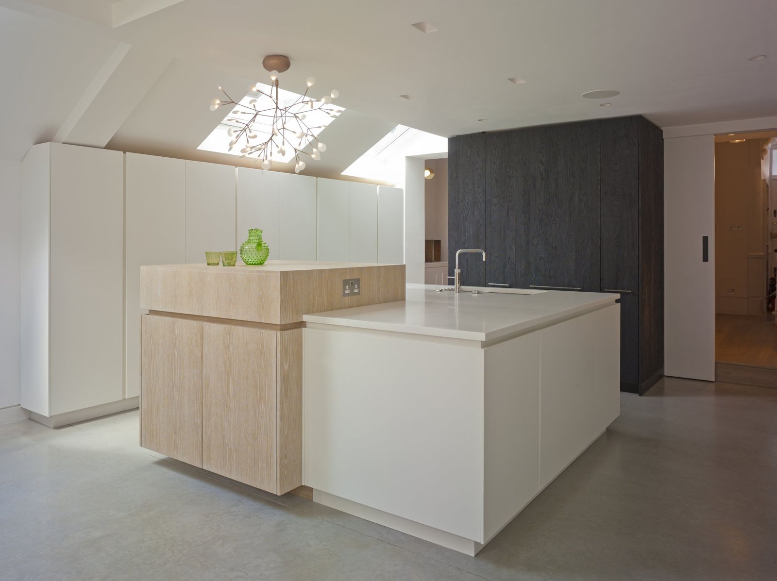 Minimal kitchen in pale oak and white with dark stained accent wall