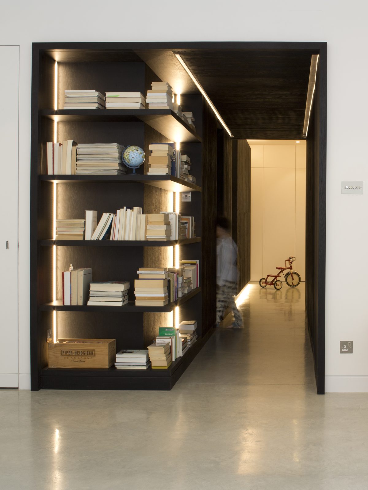 Library shelving lit within the blackened timber portal