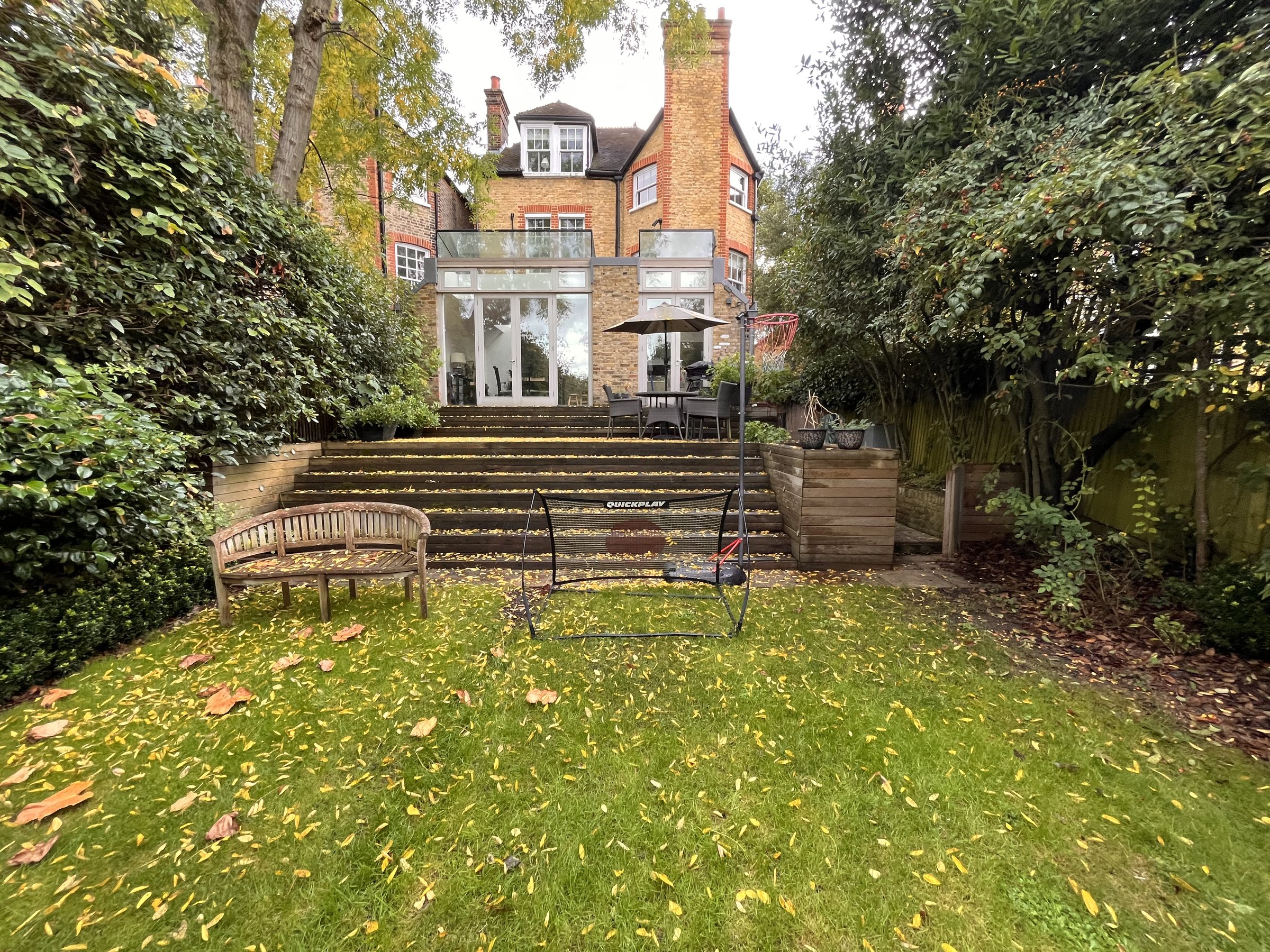 Rear elevation of the Victorian house before works, glazed rear addition and tiered timber deck stepping down to the lawn