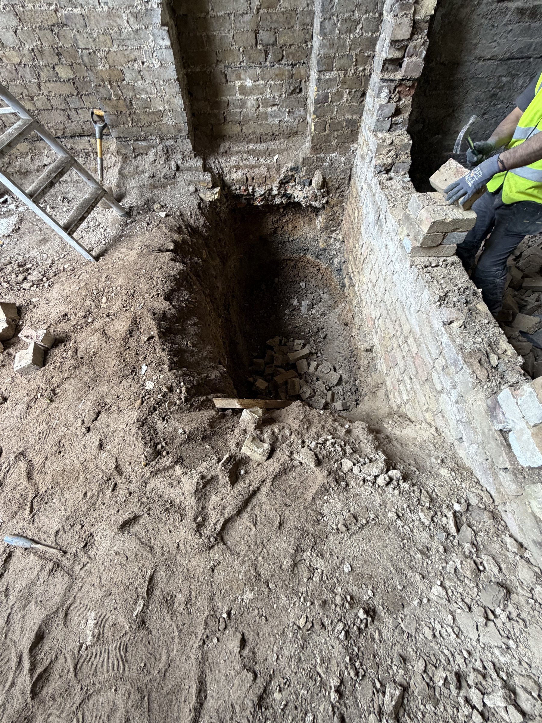 Hand-dug underpinning pit beneath the original brick footing