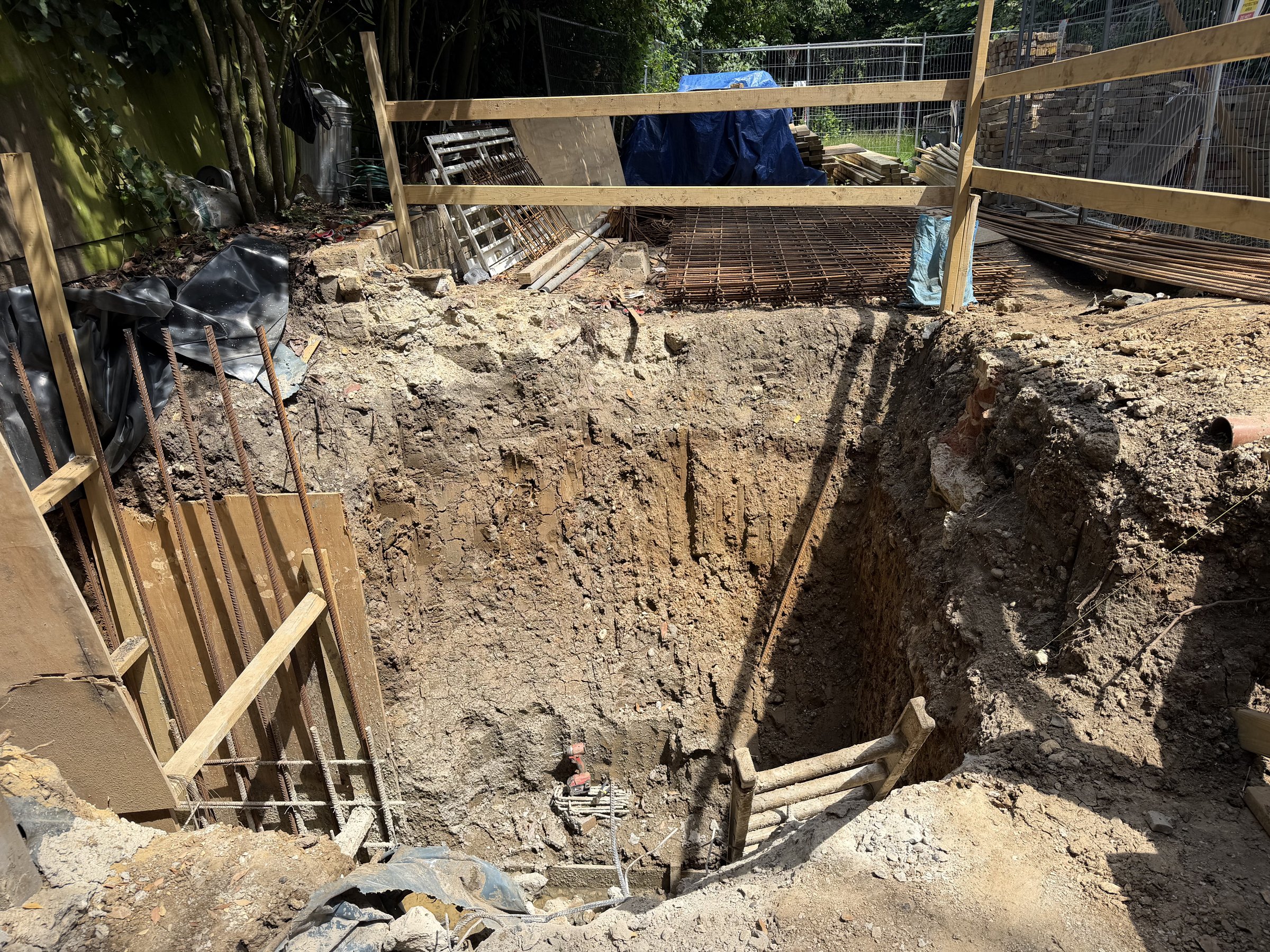 Excavation for the basement retaining wall at the rear, starter bars up and reinforcement mesh staged at the edge