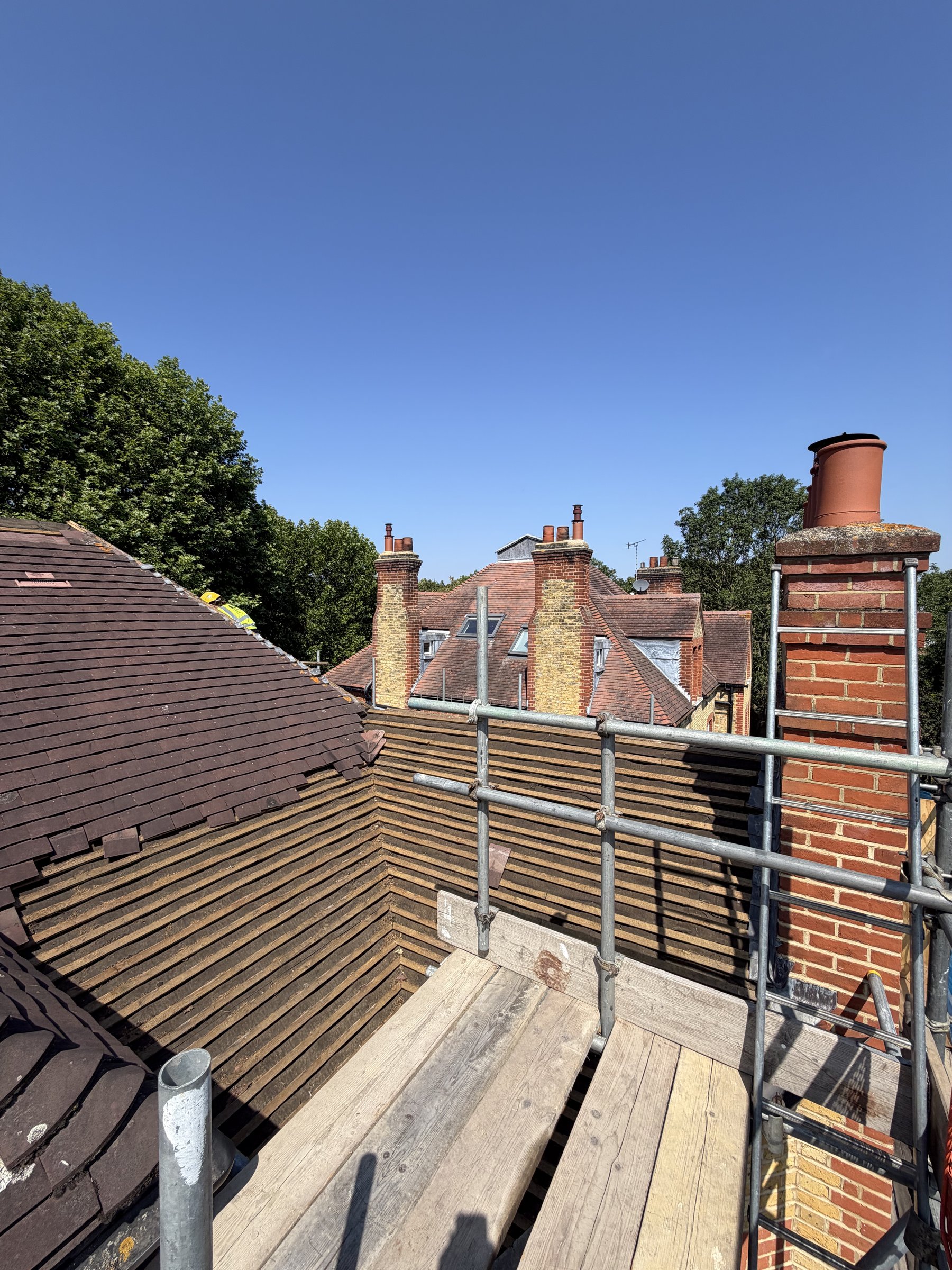 Main roof slopes stripped back to their original battens and underlay beside the chimney stack